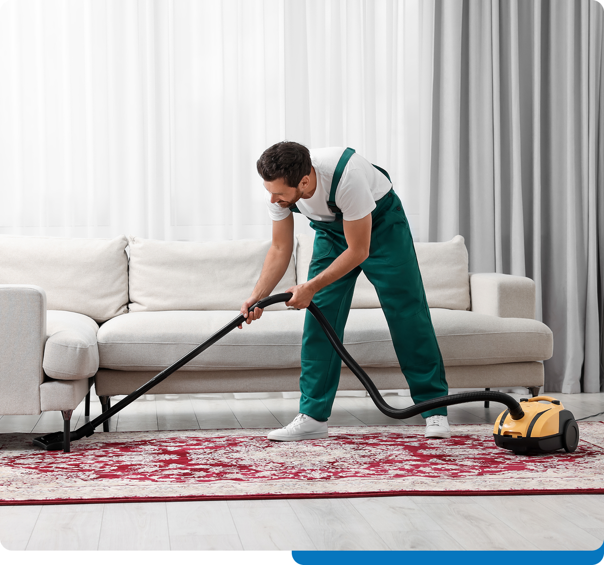 Man vacuuming red carpet in living room.
