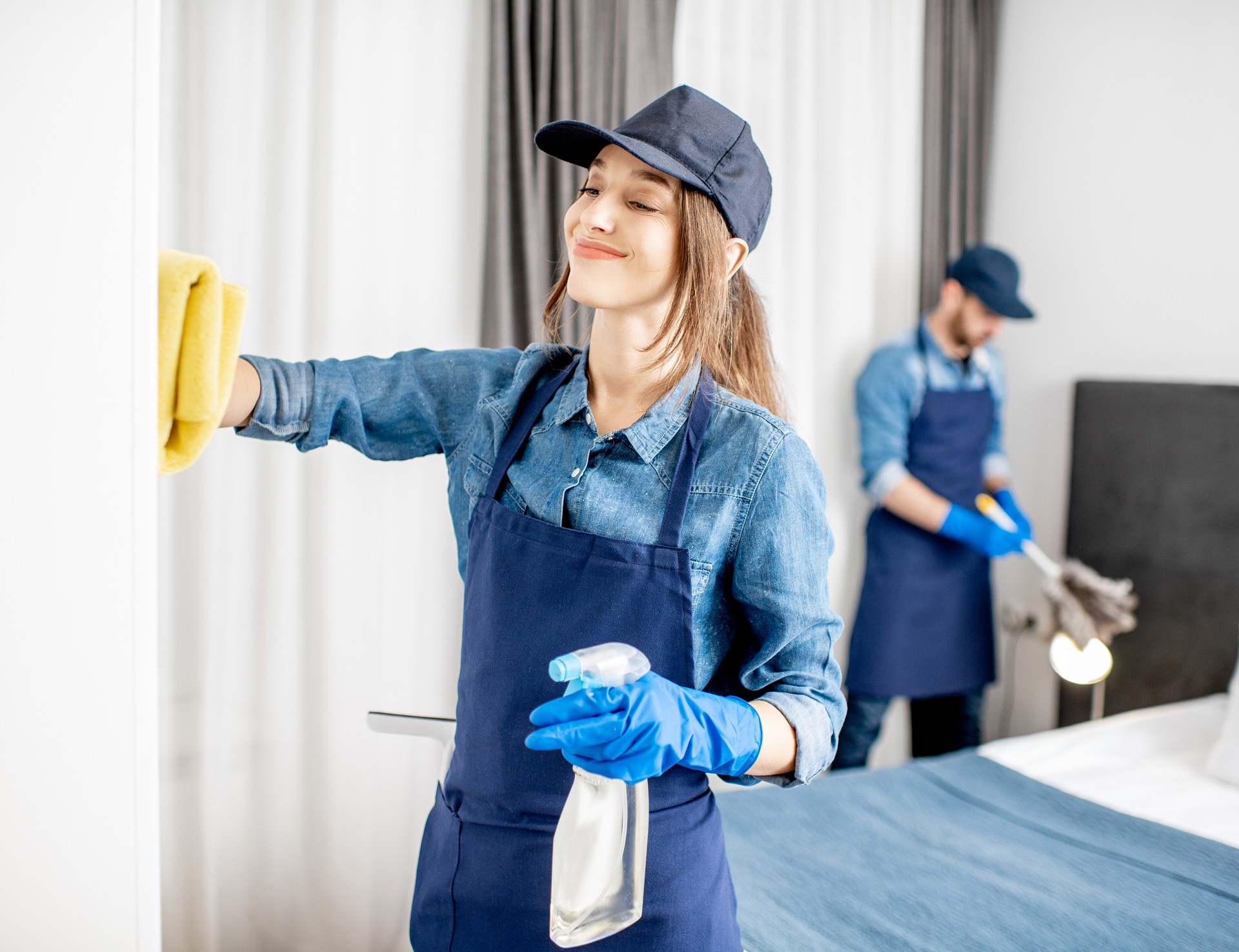 Two cleaners tidying a hotel room.